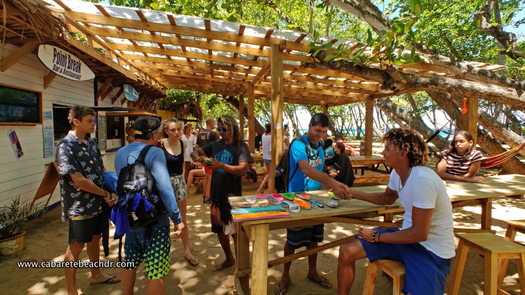 People gather around the surfing school stalls
